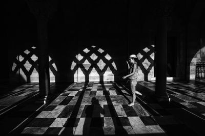 Side view of woman walking on tiled floor in building 