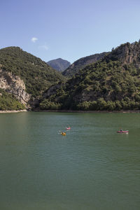 Scenic view of sea by mountains against clear sky