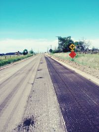 Road by railroad tracks against clear sky