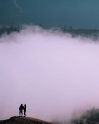 People standing on cliff against smoke