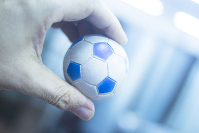 Cropped hand of person holding small soccer ball at home