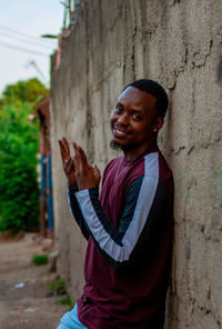 Portrait of smiling young man standing against wall