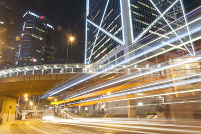 Light trails on city street by buildings at night