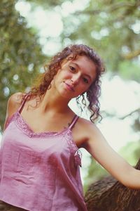 Portrait of young woman standing against tree