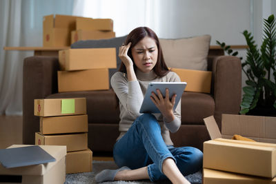 Young woman using phone while sitting on sofa at home