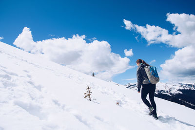 Rear view of woman walking on snowcapped mountain against sky