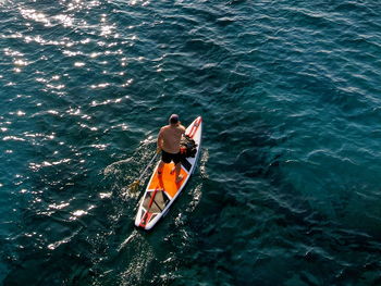 Rear view of man sitting on boat in sea