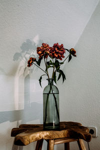Flower vase on table against wall
