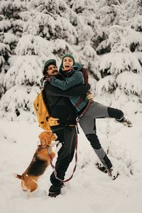 View of a couple and a dog on snow covered landscape during winter