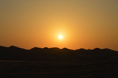 Scenic view of silhouette mountains against orange sky