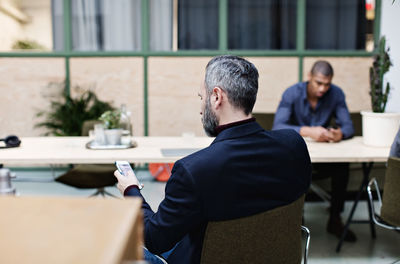 Mature businessman using mobile phone while sitting at office