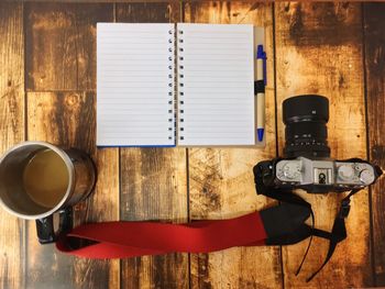 Directly above shot of camera and diary on wooden table