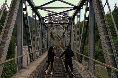 A man and a woman are walking on a railway bridge