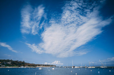 Sailboats in sea against cloudy sky