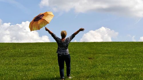 Rear view of woman standing on field against sky