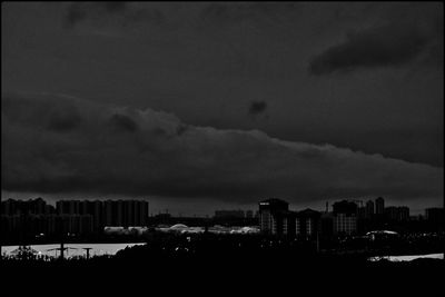 Silhouette buildings in city against sky at dusk