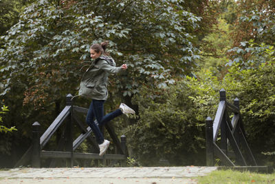 Full length of woman jumping against trees