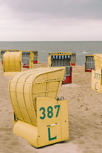 Hooded chairs on beach against sky