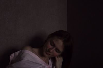 Close-up of young woman by wall at home