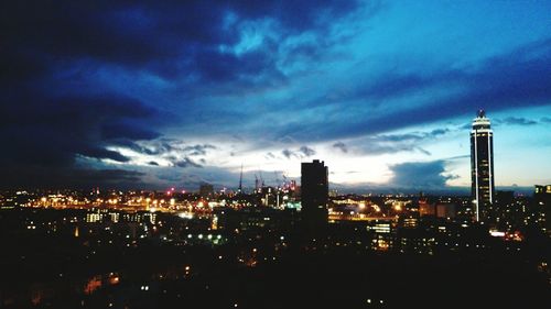 Illuminated cityscape against cloudy sky