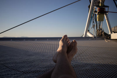 Low section of woman relaxing against clear sky