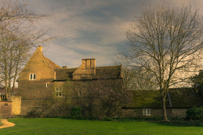 Houses and trees on field against sky