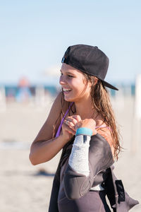 Portrait of smiling young woman drinking water at beach