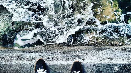 Low section of person standing on coastline