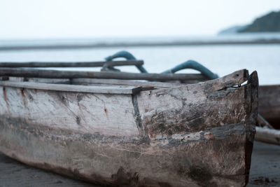 Metal boat moored on beach against sky