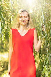 Portrait of a young blonde woman in the foliage of a weeping willow. summer time vacation.