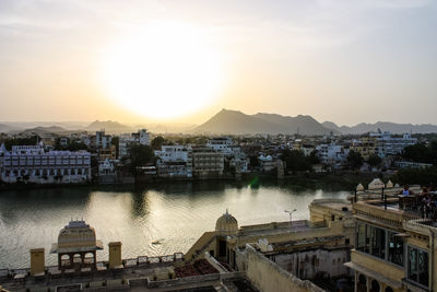 High angle view of river by buildings against sky during sunset