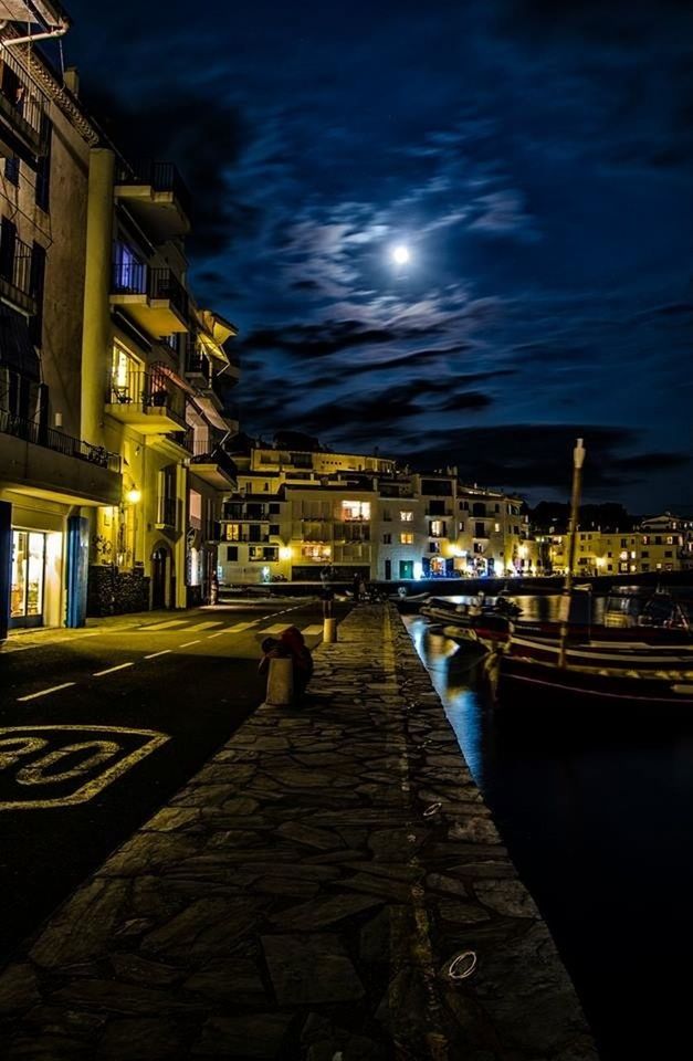 illuminated, building exterior, night, architecture, built structure, street light, sky, water, city, the way forward, lighting equipment, dusk, street, transportation, diminishing perspective, outdoors, reflection, river, cloud - sky, residential building