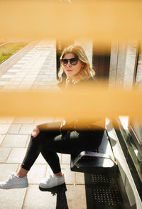 Young woman wearing sunglasses sitting outdoors