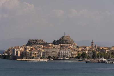 Buildings by sea against sky