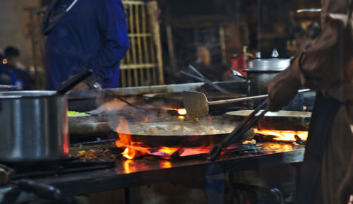 Midsection of people preparing food in kitchen