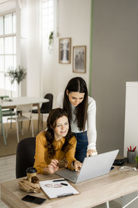 Young woman using phone while sitting on table