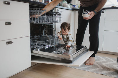 Father with toddler putting dishes into dishwasher