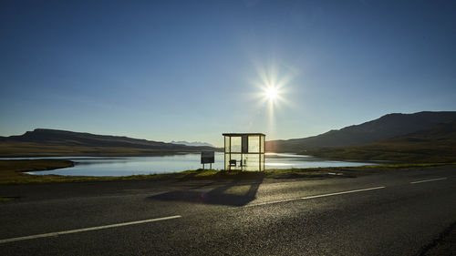 Road by lake against clear blue sky