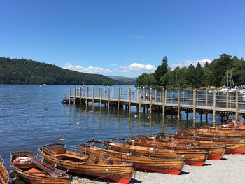 Boats moored in lake against blue sky