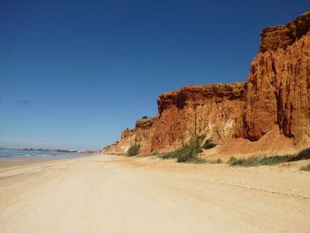 Scenic view of arid landscape against clear blue sky