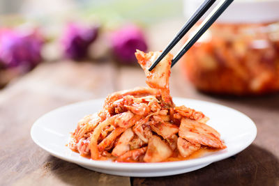 Chopsticks picking food from plate on table