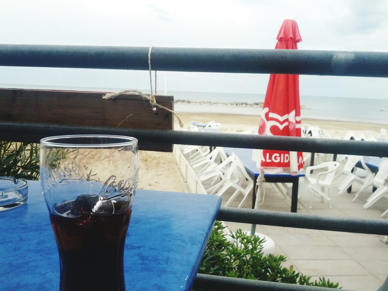 railing, red, close-up, focus on foreground, day, no people, food and drink, water, sky, freshness, wood - material, outdoors, table, metal, sea, text, sunlight, built structure, nature, still life