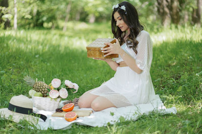 Midsection of woman holding food while sitting on grass