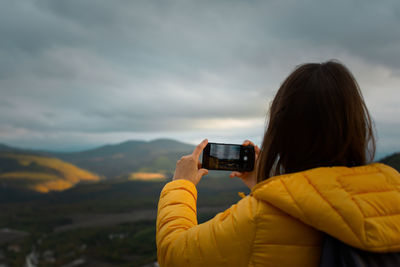 Photographer autumn landscape. a young woman tourist shoots a sunset in the mountains. 