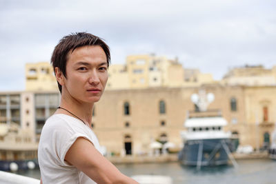 Portrait of young man standing against buildings