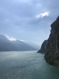 Scenic view of sea by mountains against sky