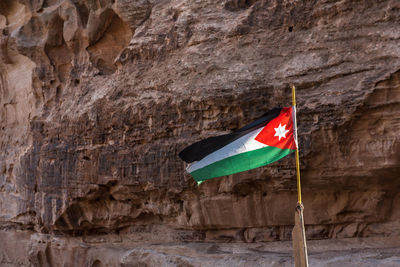 Flag of jordan with a rocky wall in the background