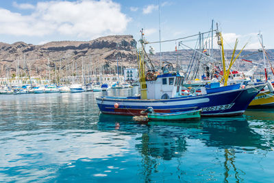 Boats moored at harbor against sky