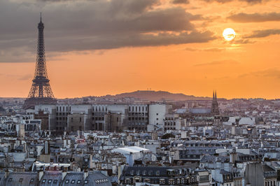 Eiffel tower in city against orange sky