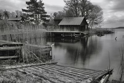 House by lake against trees and sky